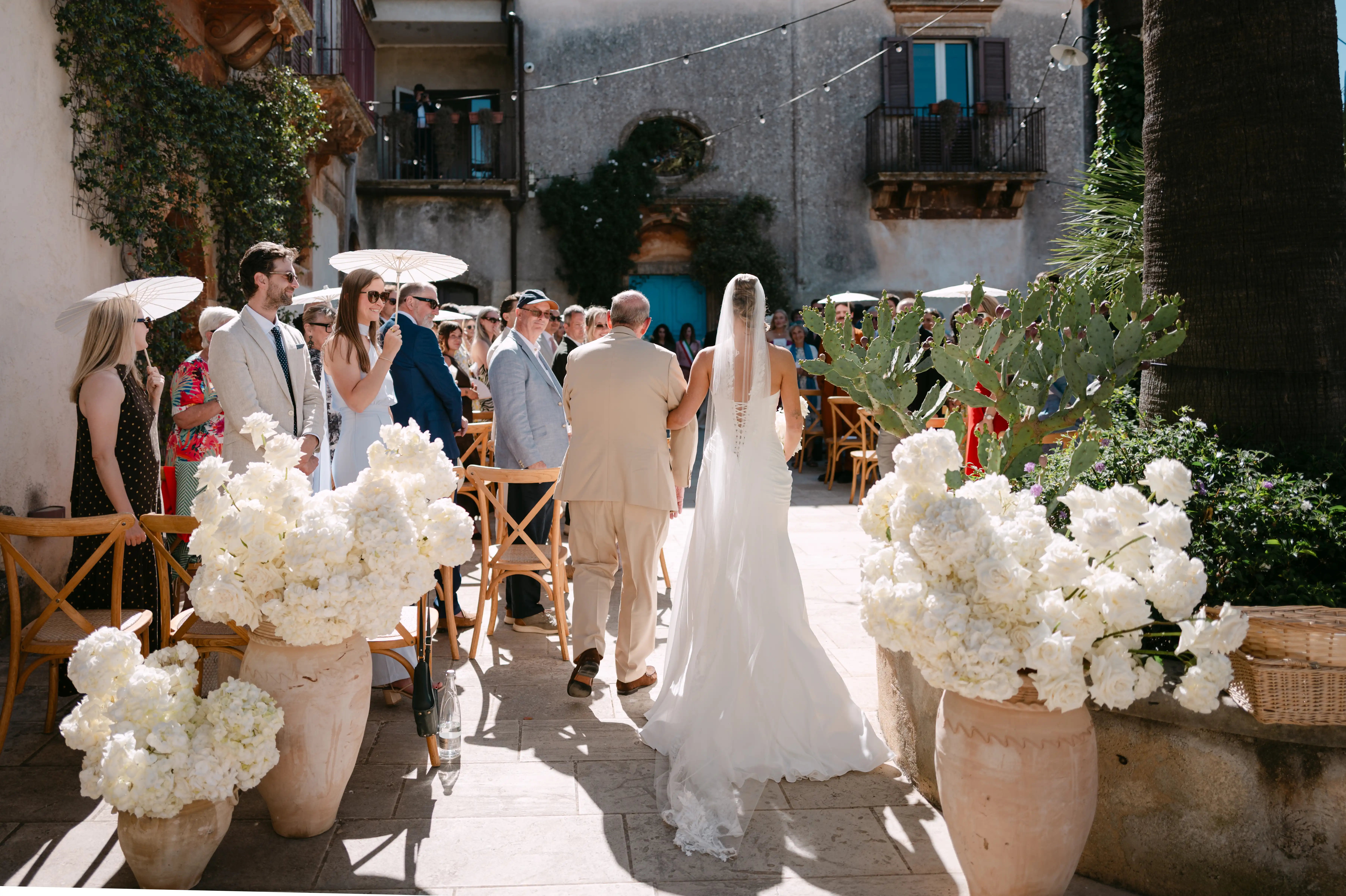 Bride walking to ceremony with her father at an elegant Italian courtyard wedding